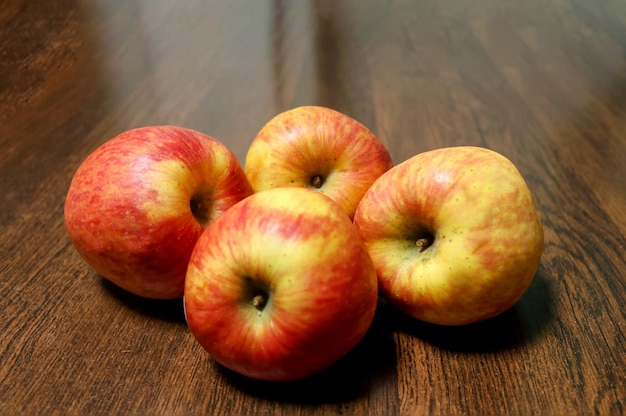 Cuatro manzanas frescas diferencian los colores en la mesa de madera