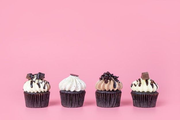 Cuatro mini muffins de chocolate Cucpake sobre fondo rosa con espacio de copia