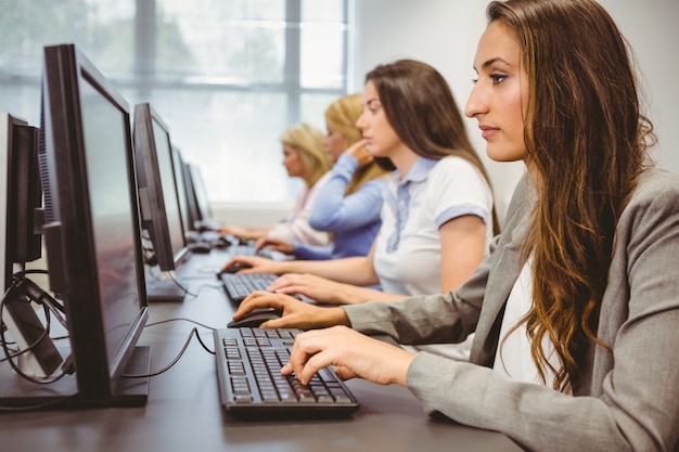 Cuatro mujeres enfocadas que trabajan en la sala de informática