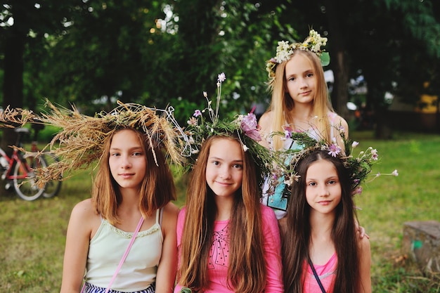 Cuatro niñas en guirnaldas de sus flores silvestres en el contexto de la naturaleza