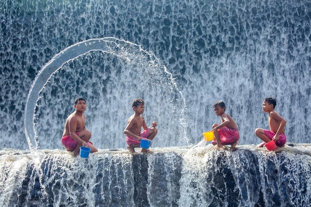 Cuatro niños balineses juegan con salpicaduras de agua en una cascada