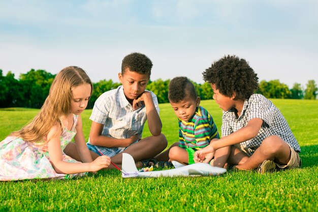 Cuatro niños felices están jugando con aviones de juguete y pintura.