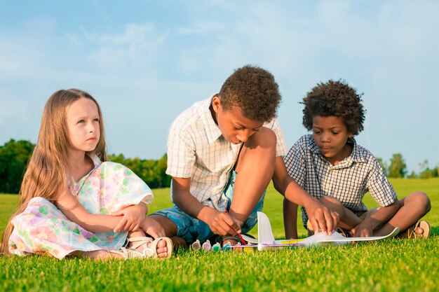 Cuatro niños felices están jugando con aviones de juguete y pintura.