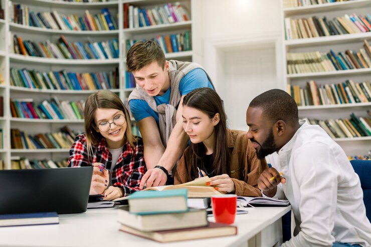 Foto cuatro niños y niñas multiétnicos sonrientes y positivos que se sientan a la mesa en la biblioteca moderna y realizan tareas en el hogar o buscan información para aprender