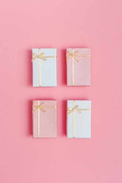 Cuatro pequeñas cajas de regalo de color rosa y blanco. Concepto o tarjeta de felicitación de estilo minimalista. Vista superior de romance