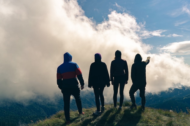 Las cuatro personas activas de pie en la montaña con una hermosa vista.