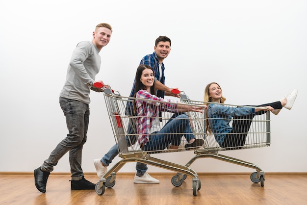 Las cuatro personas felices viajan en el carro sobre una pared blanca de fondo