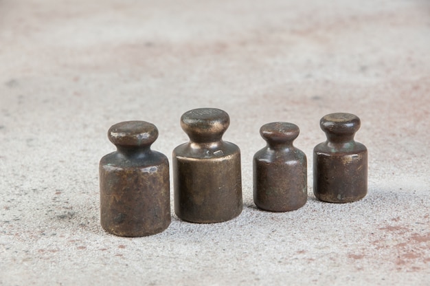 Foto cuatro pesas de bronce antiguo para escalas sobre fondo de hormigón. copie el espacio para el texto y los accesorios de fotografía de alimentos.