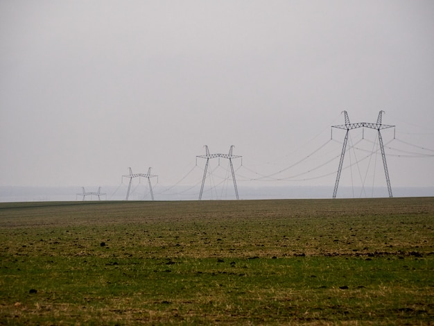 Cuatro postes de torres eléctricas en un campo brumoso