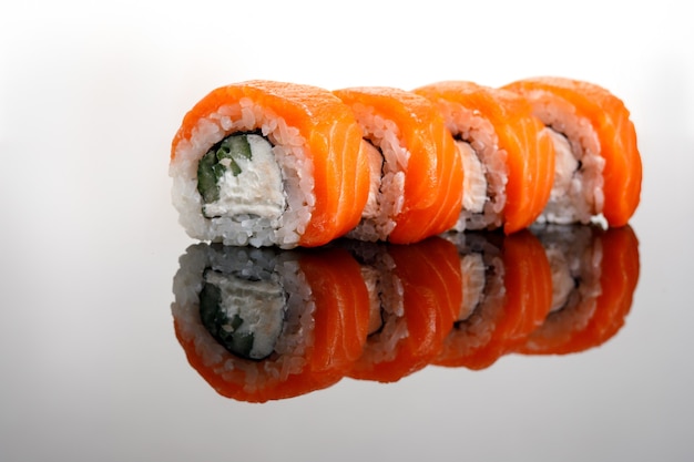 Cuatro rollos de sushi de Filadelfia sobre una mesa de cristal.