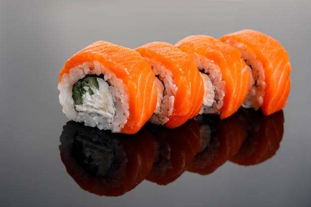 Cuatro rollos de sushi de Filadelfia sobre una mesa de cristal.