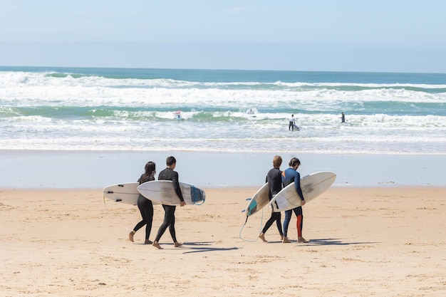 Cuatro surfistas caminan por la playa hasta el mar sosteniendo tablas