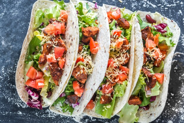 Cuatro tacos mexicanos sobre una superficie negra