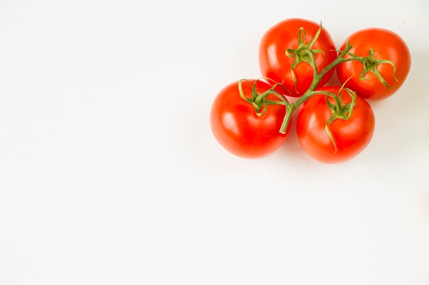 Cuatro tomates rojos sobre la mesa blanca, vegetal