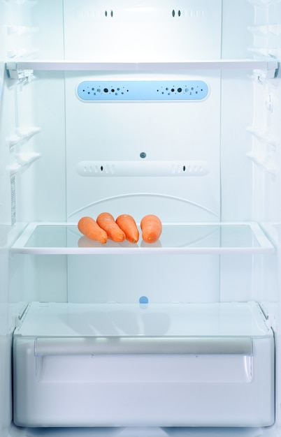 Foto cuatro zanahorias frescas y crudas en el refrigerador