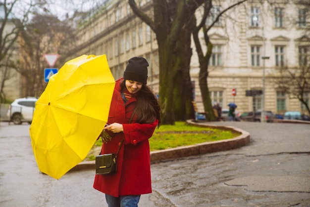 Cubierta de mujer con paraguas amarillo en alarma de tormenta de clima ventoso
