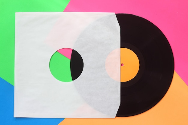 Cubierta de papel blanco envejecido y disco LP de vinilo negro aislado sobre fondo colorido