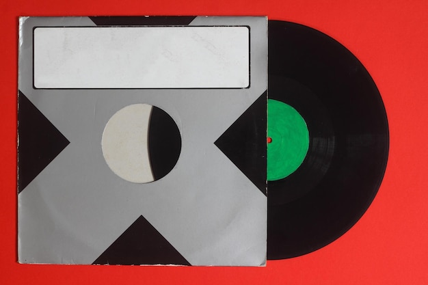 Cubierta de papel negro envejecido y disco de vinilo azul aislado en fondo rojo