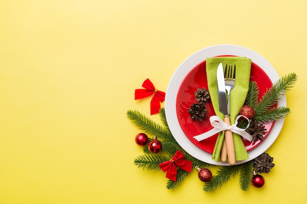 Cubierto de mesa de Navidad con decoración navideña y platos, vacas, tenedor y cuchara. Fondo de vacaciones de Navidad. Vista superior con espacio de copia.