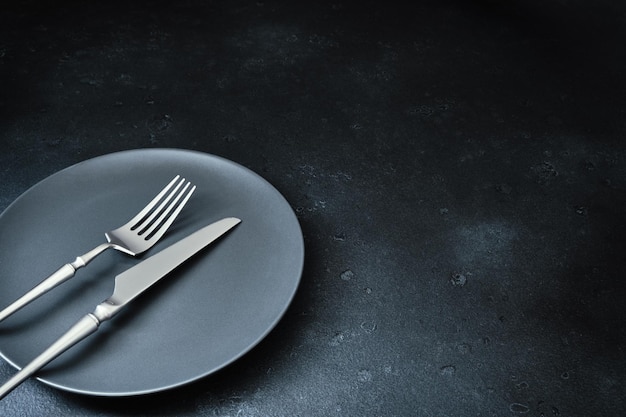 Cubiertos y platos en la mesa de fondo con textura oscura