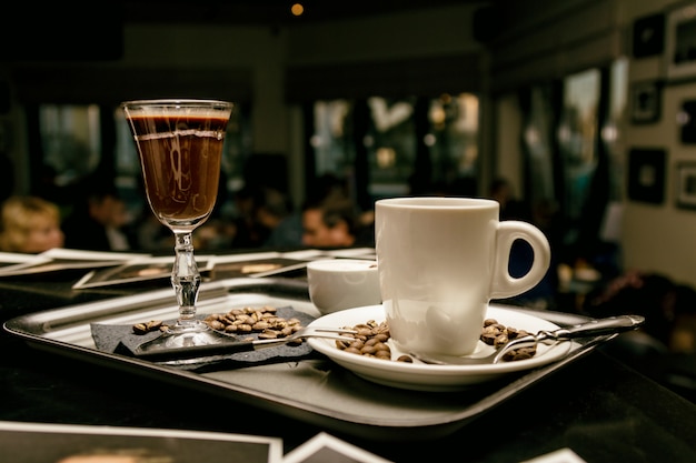 Cubiertos con vasos de café y granos de café en la cafetería de la tarde