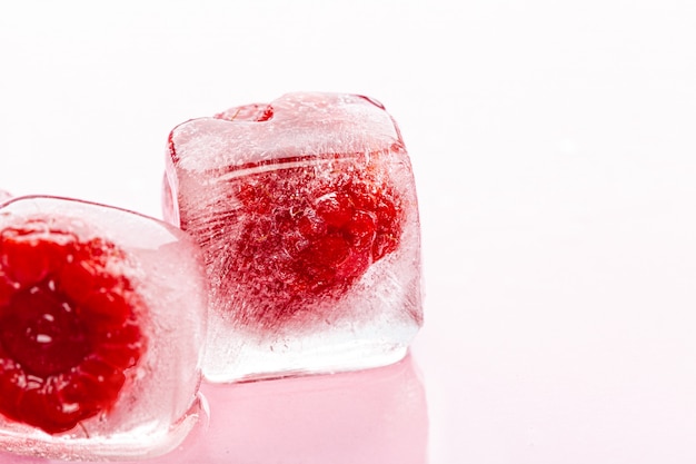 Cubitos de hielo de frambuesa sobre fondo rosa brillante