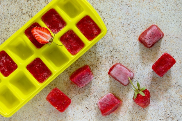 Foto cubitos de hielo con fresas sobre una piedra marrón