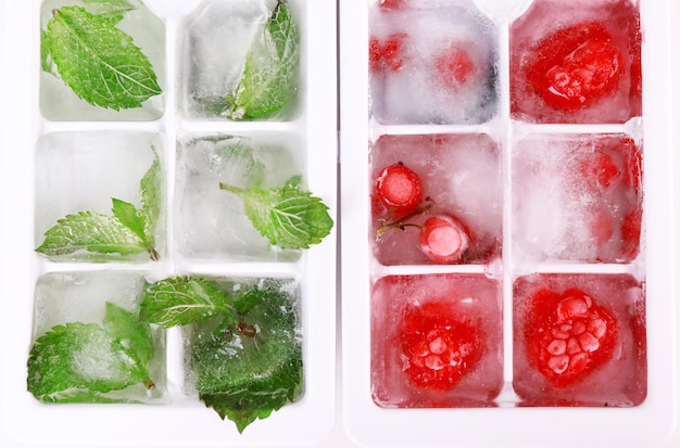 Foto cubitos de hielo con hojas de menta de bayas del bosque en primer plano de la bandeja de cubitos de hielo