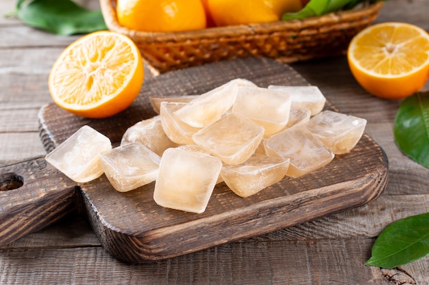 Cubitos de hielo con limón en bandeja sobre una mesa de madera, primer plano