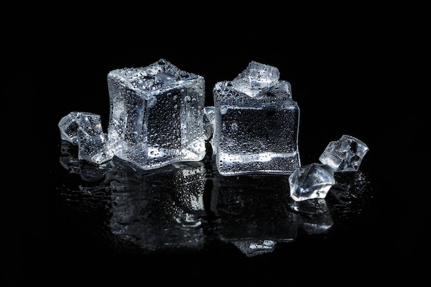 Cubitos de hielo sobre fondo negro de vidrio aislado