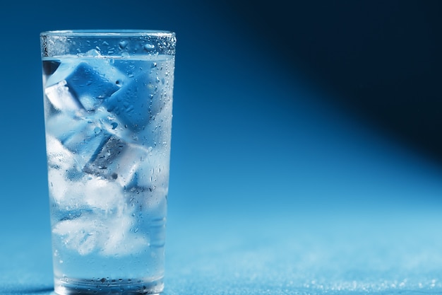 Foto cubitos de hielo en un vaso con agua cristalina en azul