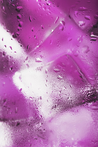 Cubitos de hielo en un vaso empañado con gotas de macro de primer plano de agua helada. Enfoque selectivo suave