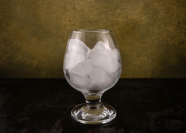 Cubitos de hielo en un vaso sobre un fondo de madera oscura.