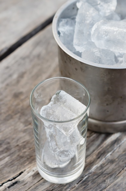 Cubitos de hielo en vaso sobre mesa de madera