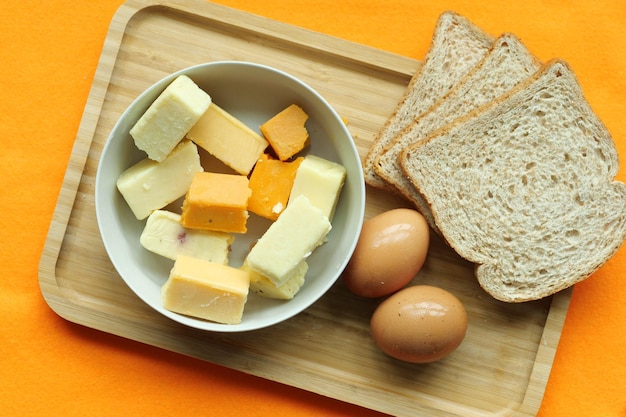 Cubitos de queso de color verde amarillo y rojo en una tabla de cortar