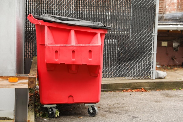 Un cubo de basura solitario en una calle urbana simboliza el consumo de residuos y se pasa por alto el deterioro en medio de la vida de la ciudad