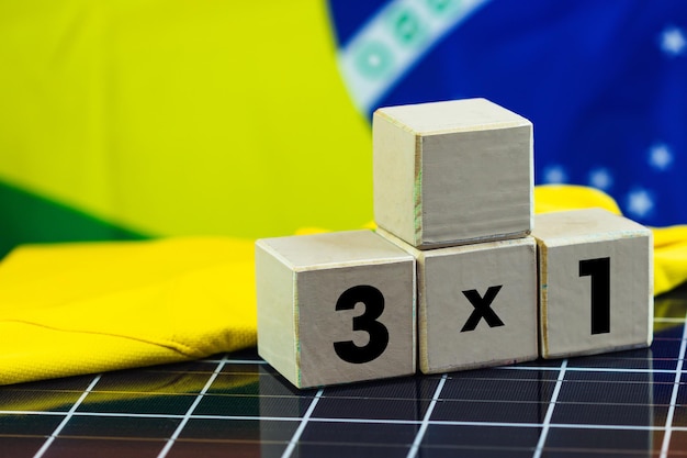 Cubo de bloques de madera con juegos de resultados numéricos y bandera de Brasil en panel solar fotovoltaico Concepto deportivo y de energía limpia