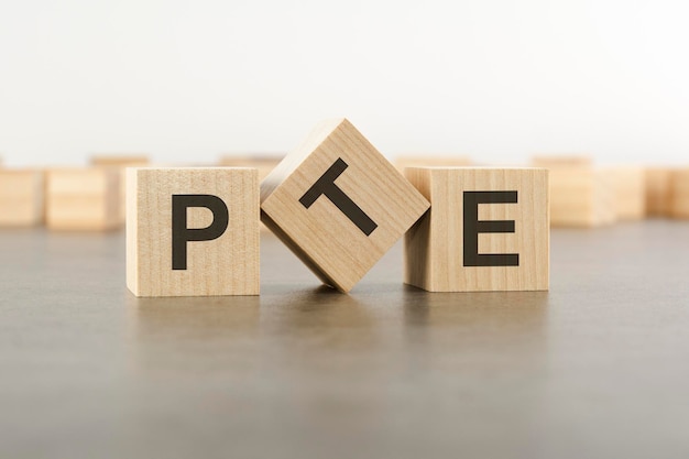 Cubo de madeira com a letra da palavra PTE cubos de madeira sobre fundo cinza PTE curto para Pearson Tests of English