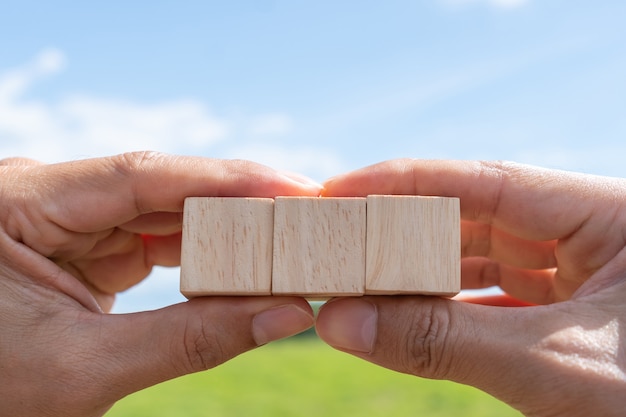 Cubo de madeira em branco no qual você pode colocar texto ou ícone na mão segura o fundo