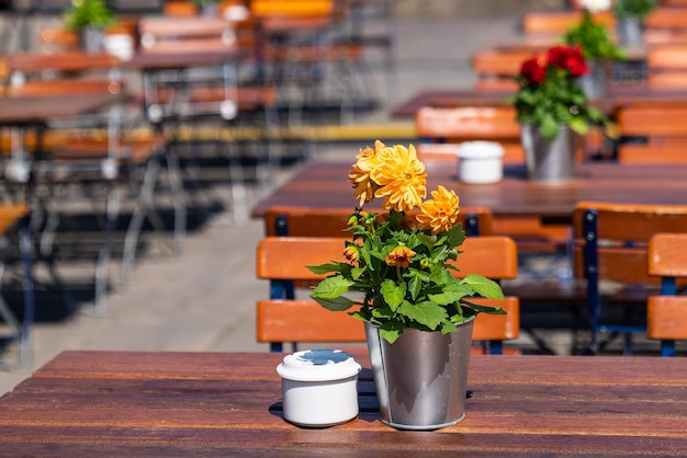 Cubo de estaño decorativo con flores en flor y un cenicero en la mesa de un café callejero