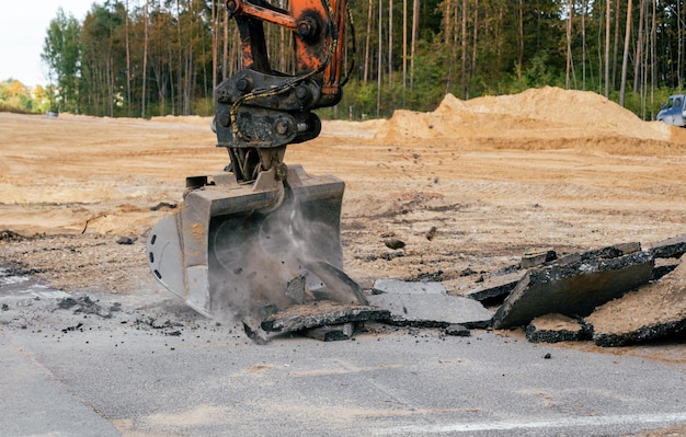 Cubo de excavadora rompe asfalto viejo Sitio de construcción