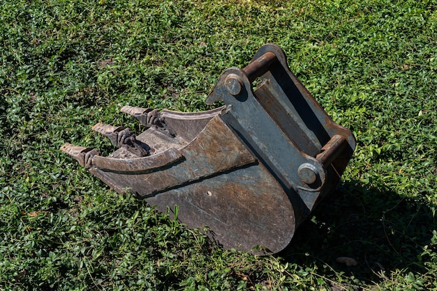 Cubo de excavadora tirado en la hierba verde