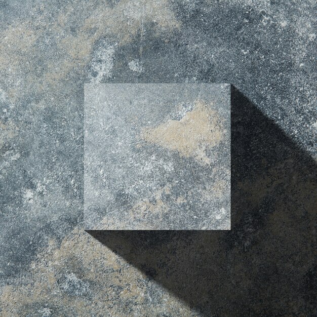Cubo de granito con sombra aislado sobre fondo de piedra oscura, plano laical