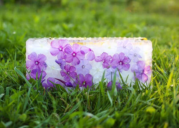 Cubo de hielo con flores sobre la hierba verde en verano.