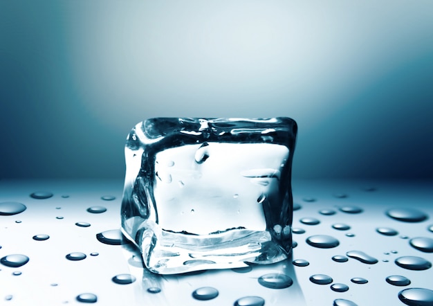 Cubo de hielo con gotas de agua aisladas sobre fondo azul brillante