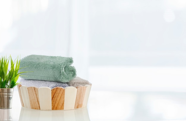 Cubo de madera del baño con las toallas en la tabla blanca.