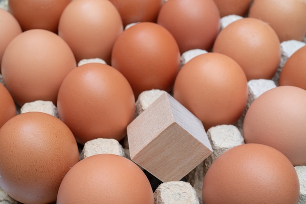 Cubo de madera uno entre huevos de gallina.