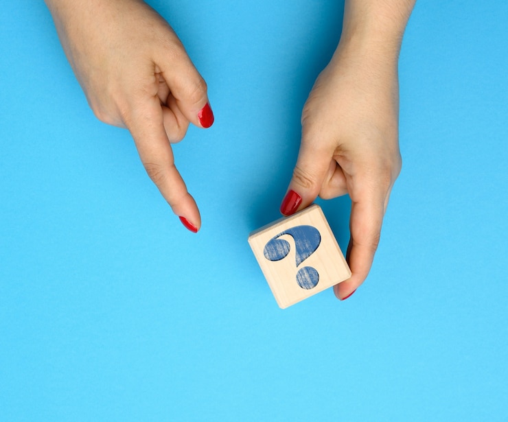 Foto cubo de madera con un signo de interrogación sobre un fondo azul, concepto de respuestas y preguntas, suspenso