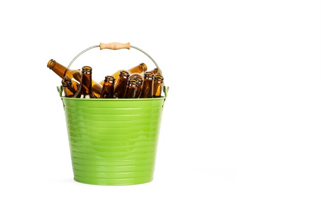 Un cubo de metal verde con un montón de botellas de cerveza vacías en un blanco