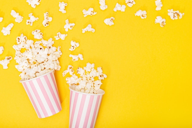 Cubo de palomitas de maíz sobre fondo amarillo. fondo de película o televisión. vista superior copia espacio